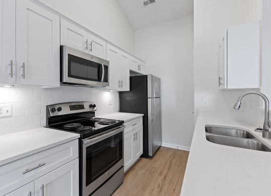 an all white kitchen with stainless steel appliances and white cabinets at Four Bridges, Liberty Township