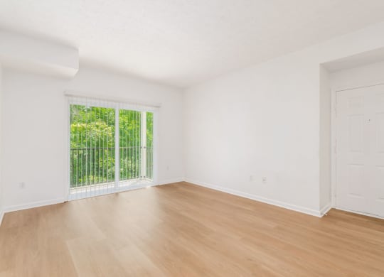 an empty living room with wood floors and a window