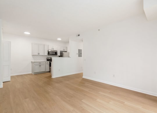an empty living room and kitchen with white walls and wood floors
