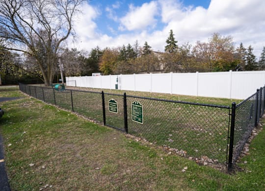 a chain link fence with two signs on it in a field