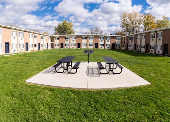 a courtyard with picnic tables in front of an apartment building