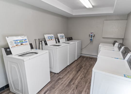 a laundry room with four washers and dryers and a row of washing machines