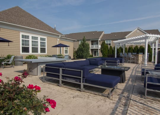 a large patio with blue couches and chairs and a table with a ping pong table