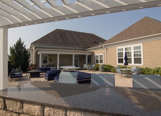 an outdoor entertaining area with a stone wall and a white pergola  at Grove City Summit, Grove City