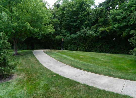 Sidewalk through a park with grass and trees at Honey Creek, Greenwood, IN
