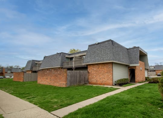 a brick house with a grey roof and a sidewalk at Rivers Edge Apartments and Townhomes, Dayton