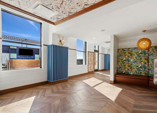 A room with wooden floors and a large window with a view of the sky.