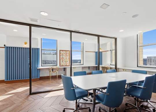 A conference room with a long table and blue chairs.