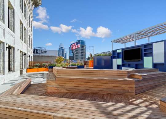 A wooden deck with a metal pergola and a building with the sign