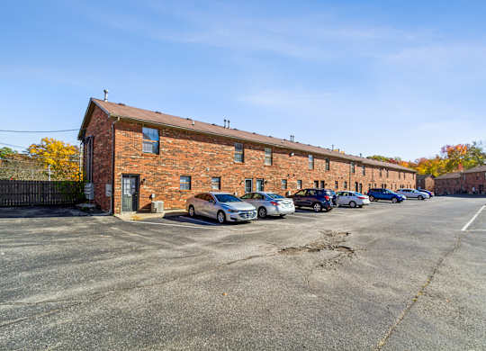 A parking lot with cars and a brick building.