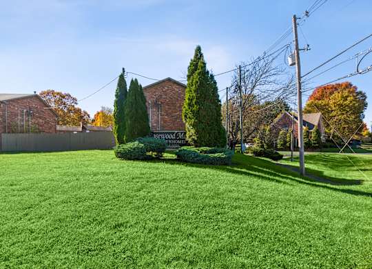A green lawn in front of a brick building with a sign that says