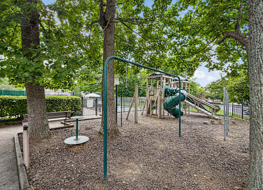 A playground with a green slide and a swing set.