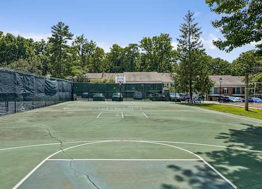 A tennis court surrounded by a fence and trees.