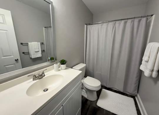 A bathroom with a white sink, toilet, and a white shower curtain.