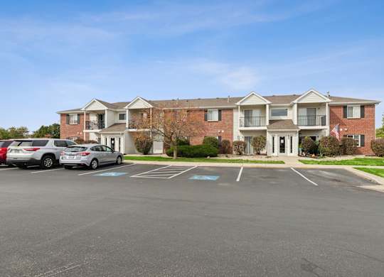 A large red brick building with a parking lot in front.