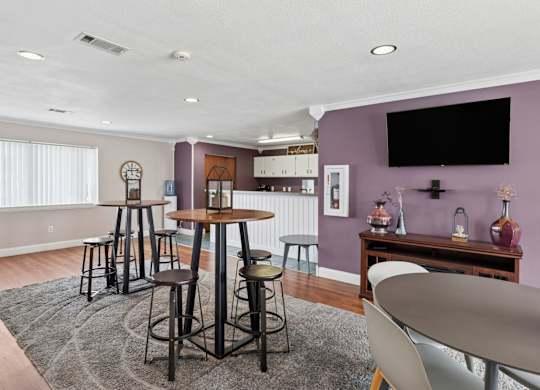 A room with a purple wall and a black television mounted on it.