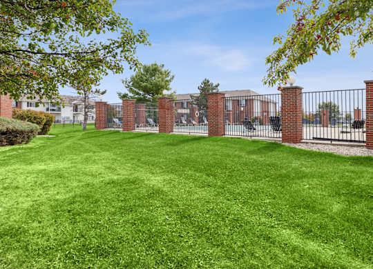 A green lawn with a fence and a building in the background.