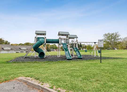 A playground with a green slide and a white sign.