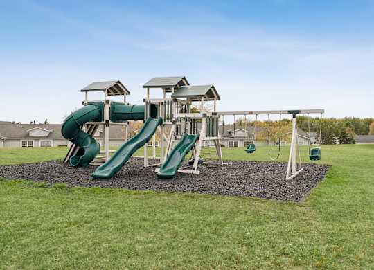 A playground with a green slide and a white structure.