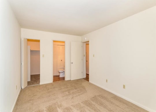 an empty living room with a bathroom in the background