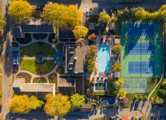 a birds eye view of a tennis court with trees and a pool