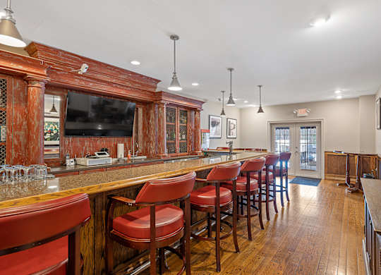 a bar with red chairs in a room with a television at Indian Creek Apartments*, Ohio