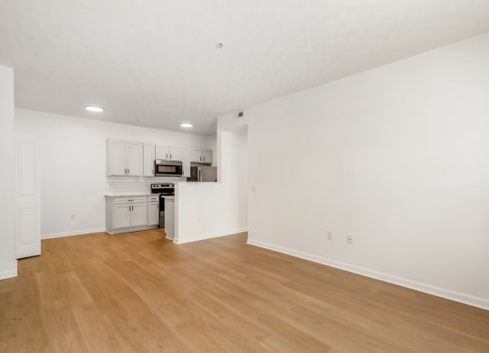 an empty living room and kitchen with white walls and wood floors