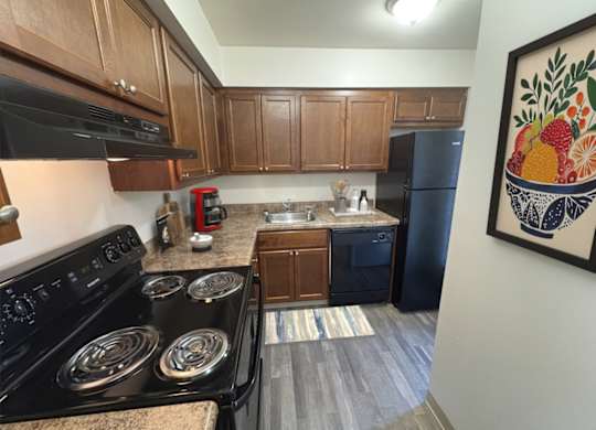 A kitchen with a black stove top oven and a black refrigerator.