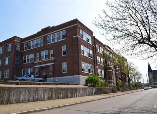 A large red brick building with a blue truck parked in front.