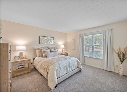 A bedroom with a large bed and a window with curtains.