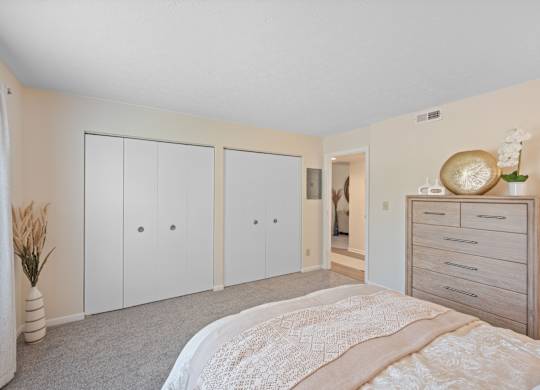 A bedroom with a bed, dresser, and wardrobe.