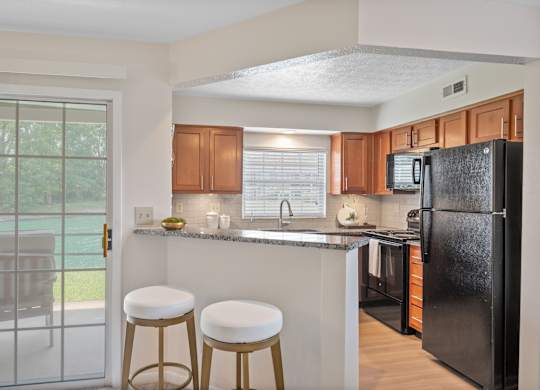 A kitchen with a black refrigerator and white countertops.
