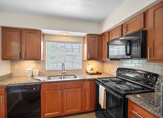A kitchen with black appliances and wooden cabinets.