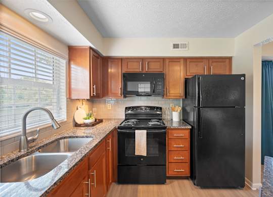 A black refrigerator sits in a kitchen with wooden cabinets.