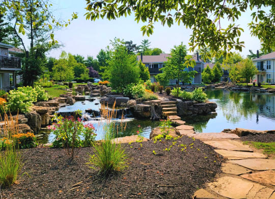 a garden with a pond and bridge in front of a building at Harpers Point Apartments, Ohio, 45249