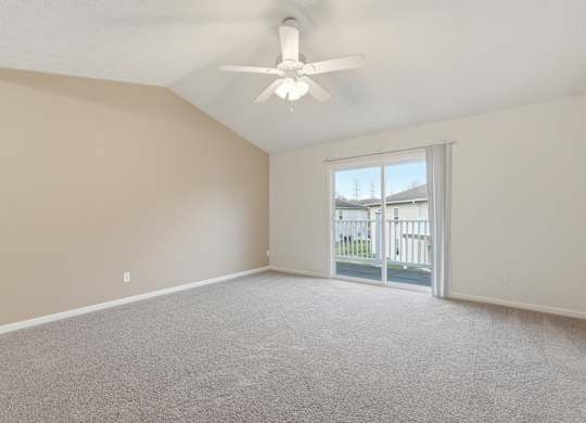 A room with a ceiling fan and a sliding glass door leading to a balcony.