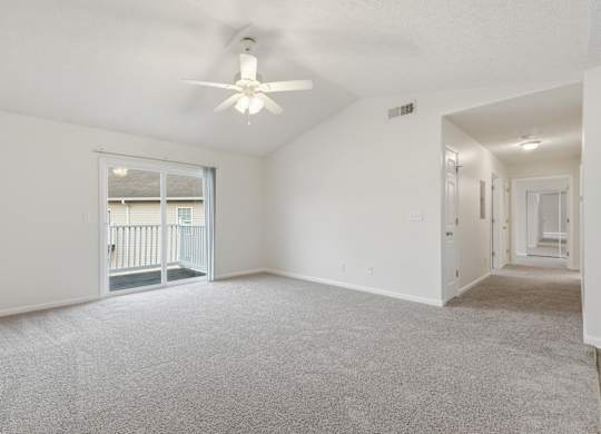 A spacious room with a ceiling fan and carpeted floor.