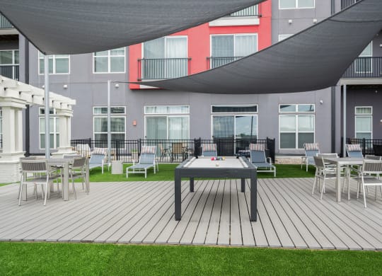 West Chester OH pet Friendly Apartments - Liberty Center - Outdoor Recreation Area with Pool Table, Lounge Chairs, Tables, Egg Chairs, Turf, Fire Pit, and Canopy Cover
