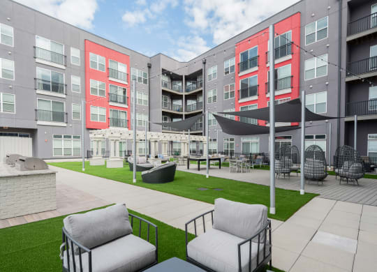 an outdoor area with chairs and a lawn in front of an apartment building