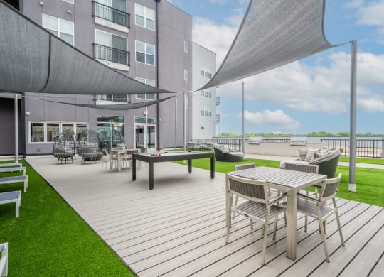 a patio area with tables and chairs and a building in the background