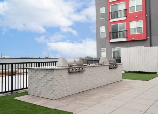 the outdoor patio of an apartment building with a barbecue grill