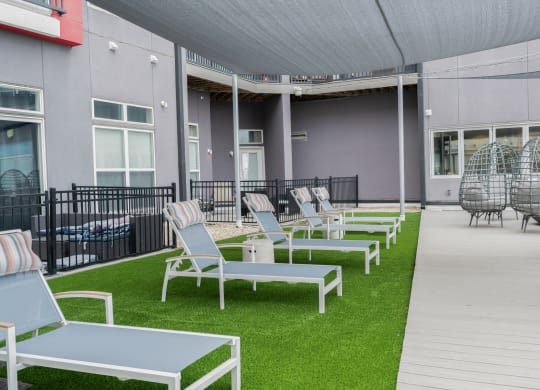 a row of lounge chairs and tables on the grass outside of a building