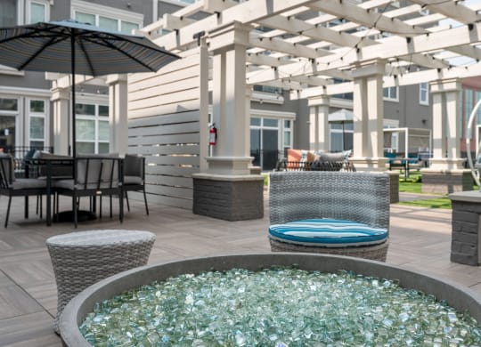 a patio with a fire pit and tables with umbrellas