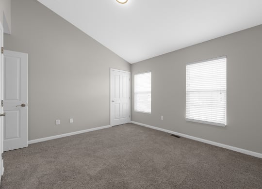 an empty living room with a door and two windows at Traditions at Slate Ridge, Reynoldsburg Ohio