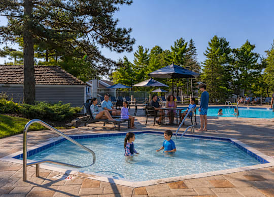 A group of people are enjoying a sunny day at a poolside.