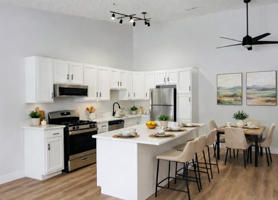A modern kitchen with white cabinets and a dining table set for four.