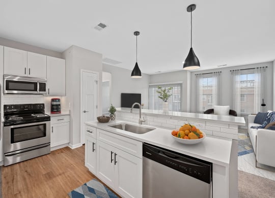 a white kitchen with a large counter top and a sink at Monmouth Row Apartments, Newport, KY, 41071