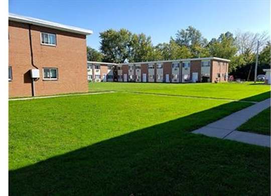 A grassy area in front of a building with a clear blue sky.