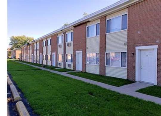 A long row of houses with green lawns in front.