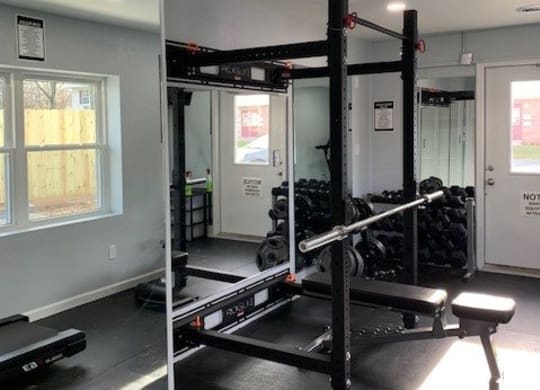 A gym with a squat rack and a bench.